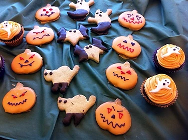 Halloween cupcakes and iced biscuits decorated with spooky faces and shapes